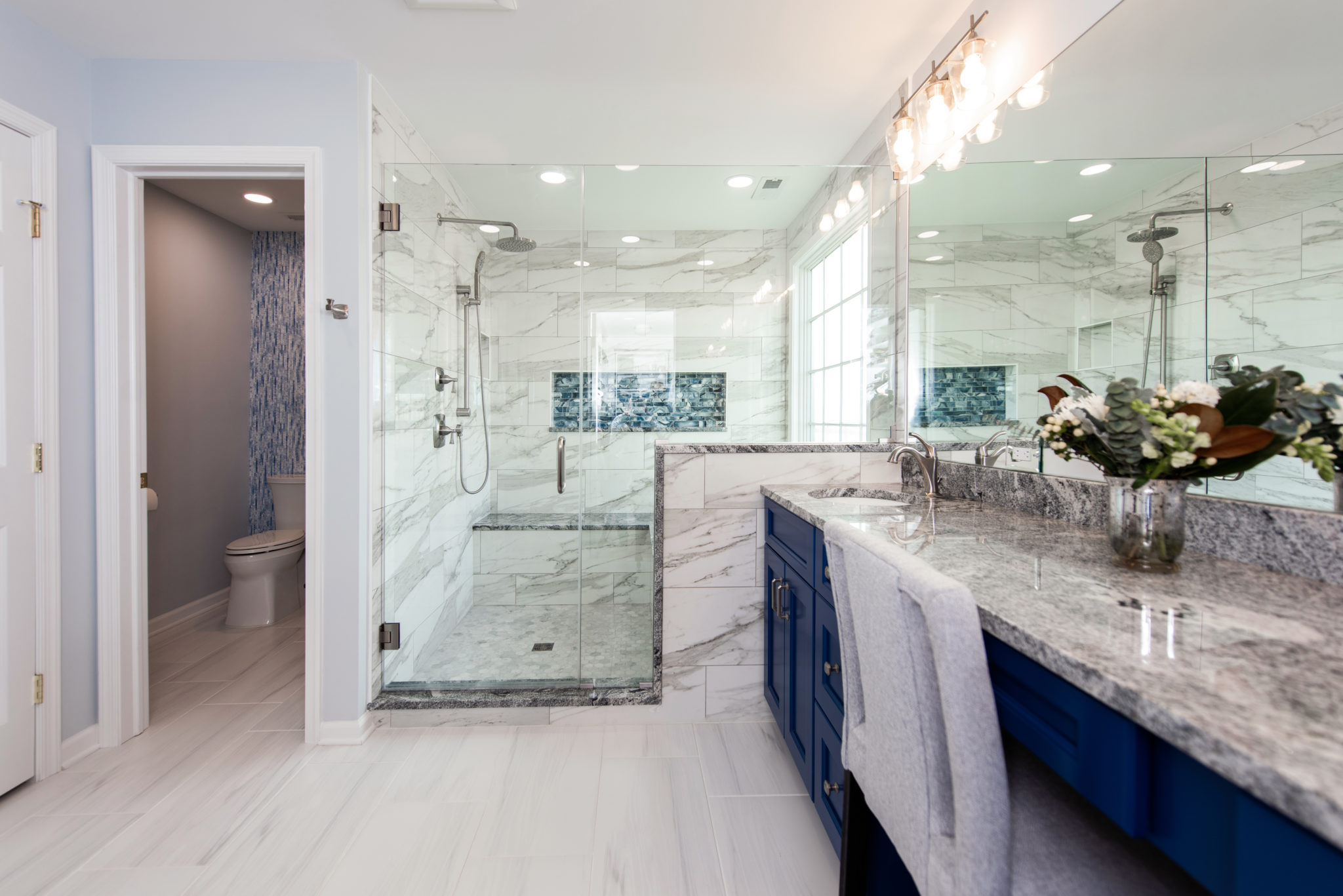 Renovated bathroom with blue cabinets and large shower from Amiano and son